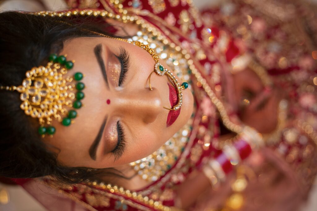 Stunning Indian bride in traditional attire and bridal jewelry, eyes closed.